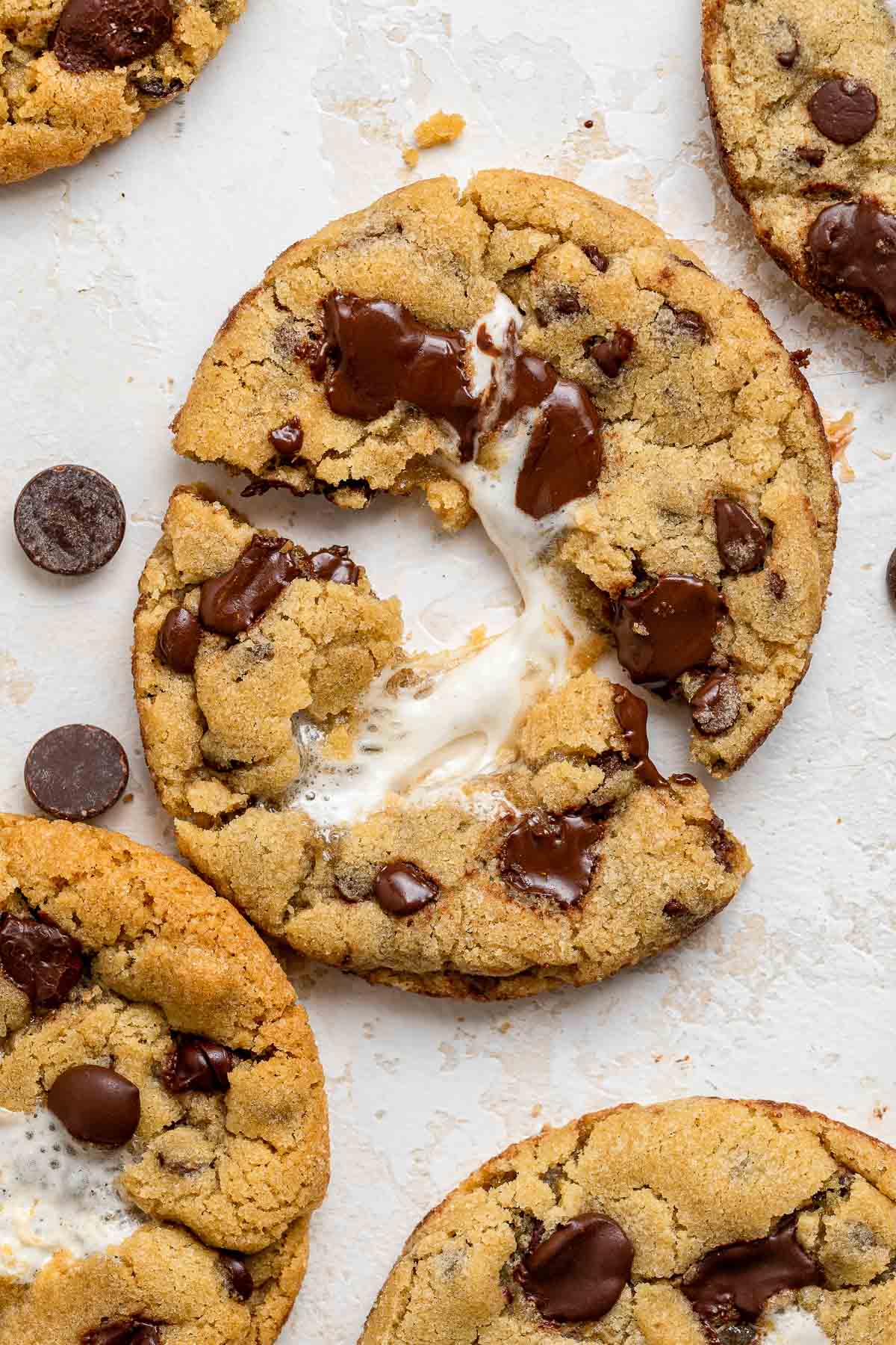 Chocolate chip cookie ripped in the center with gooey center showing.