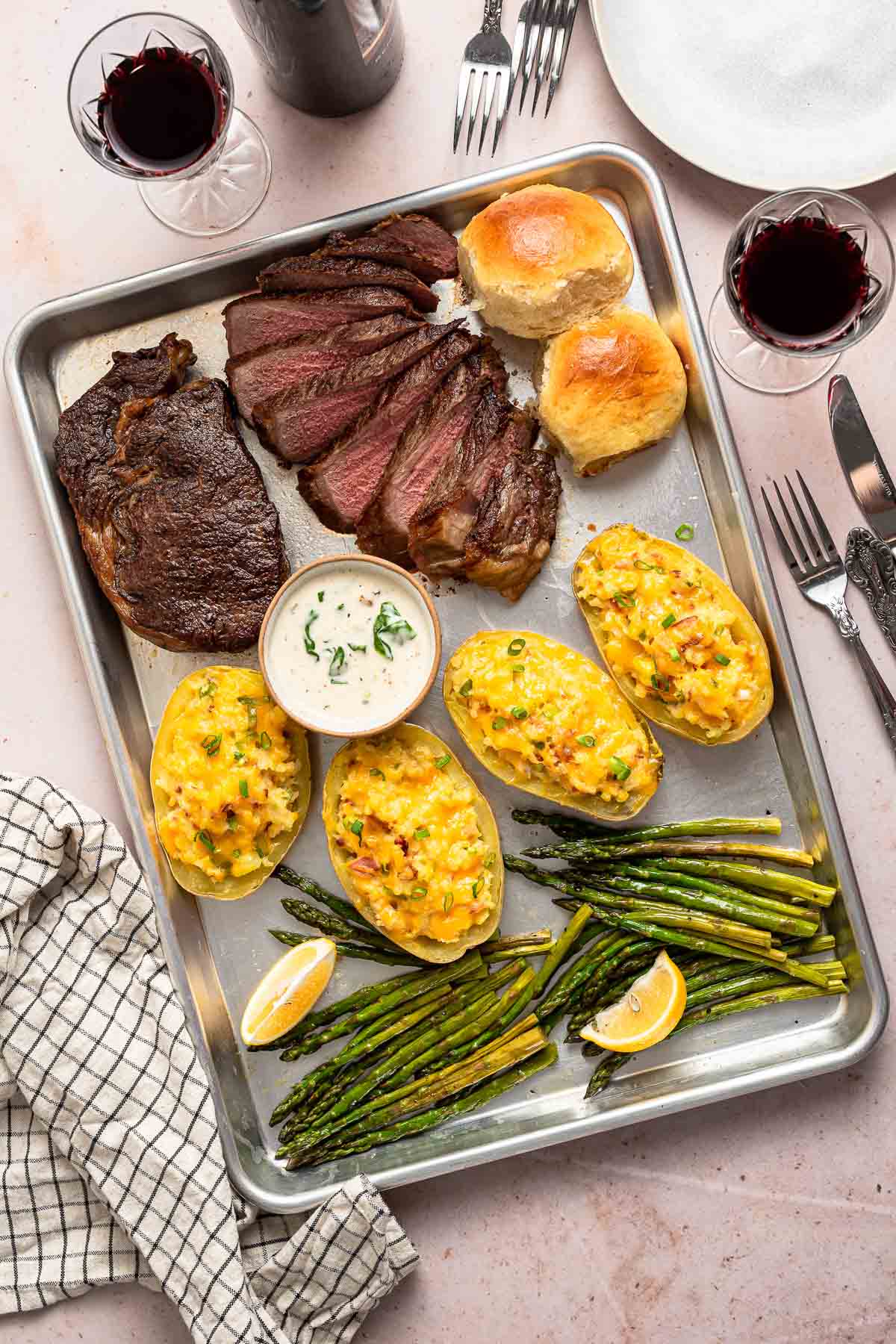 Sheet pan dinner with steak, potatoes, rolls, and asparagus.