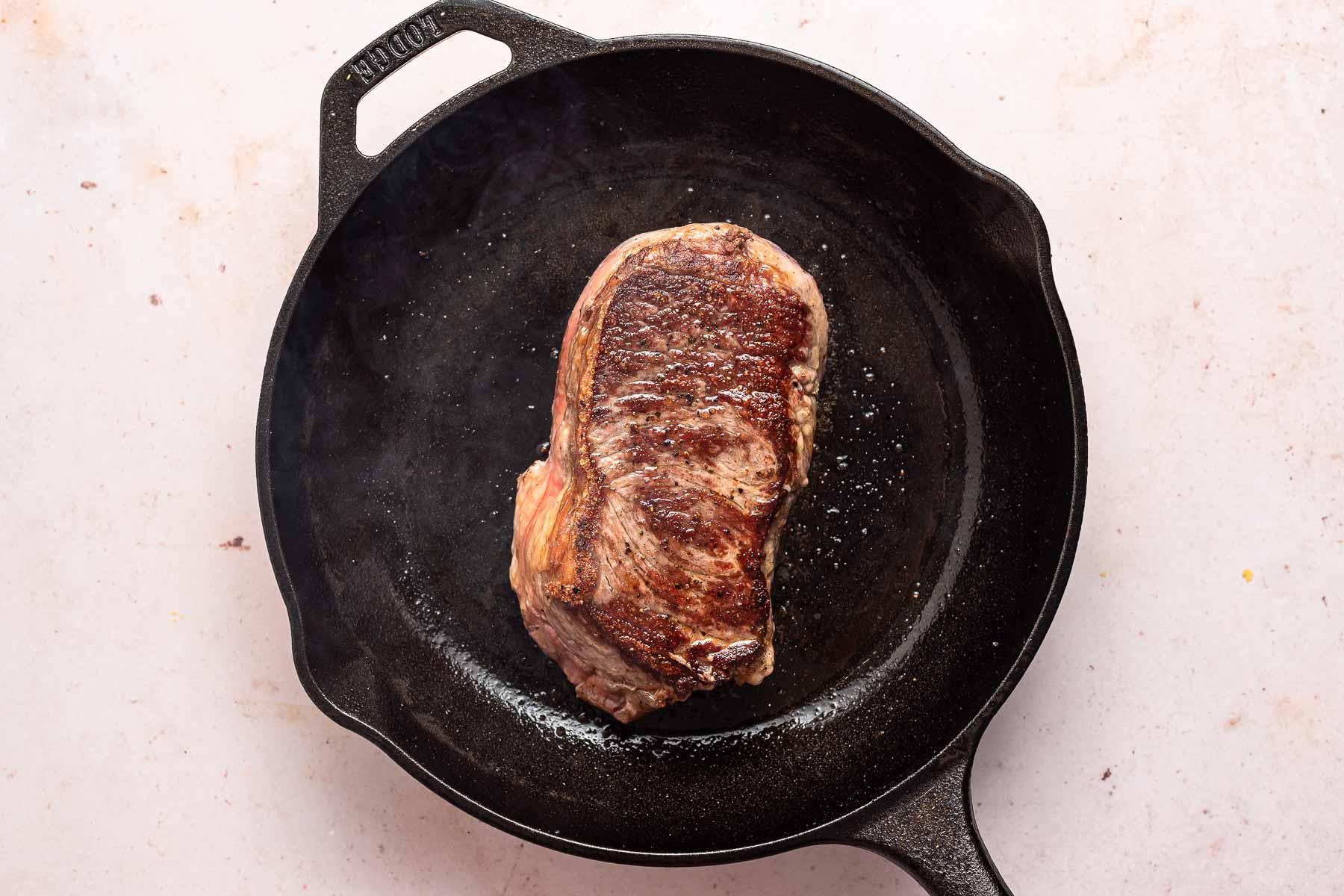 Steak cooking in cast iron skillet.