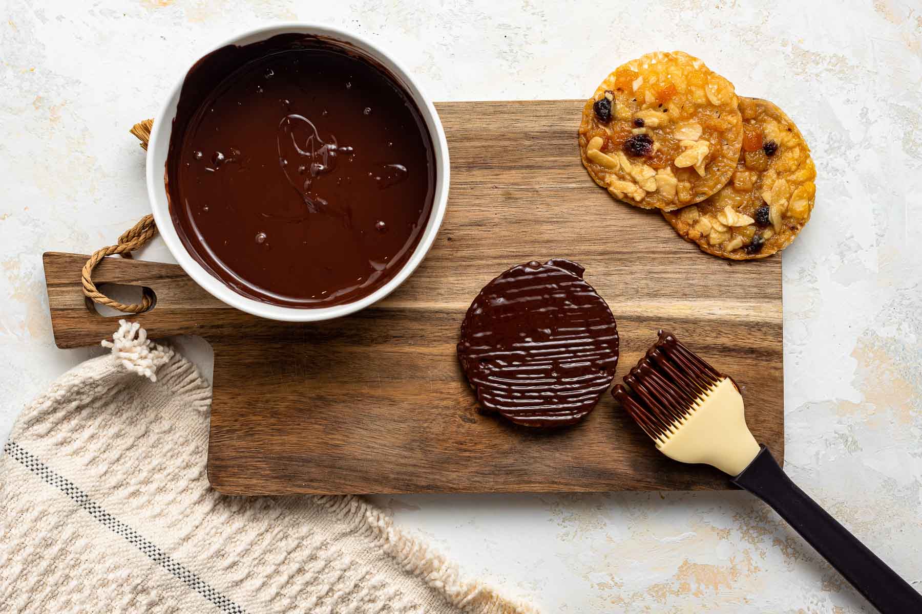 Brushing chocolate on the underside of cookies.
