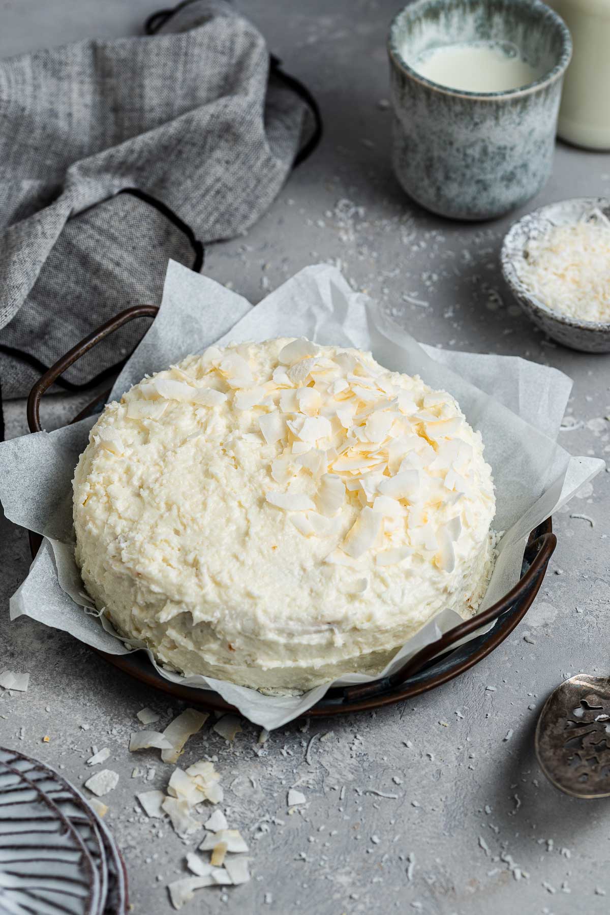 Small white coconut cake decorated with fresh coconut flakes.