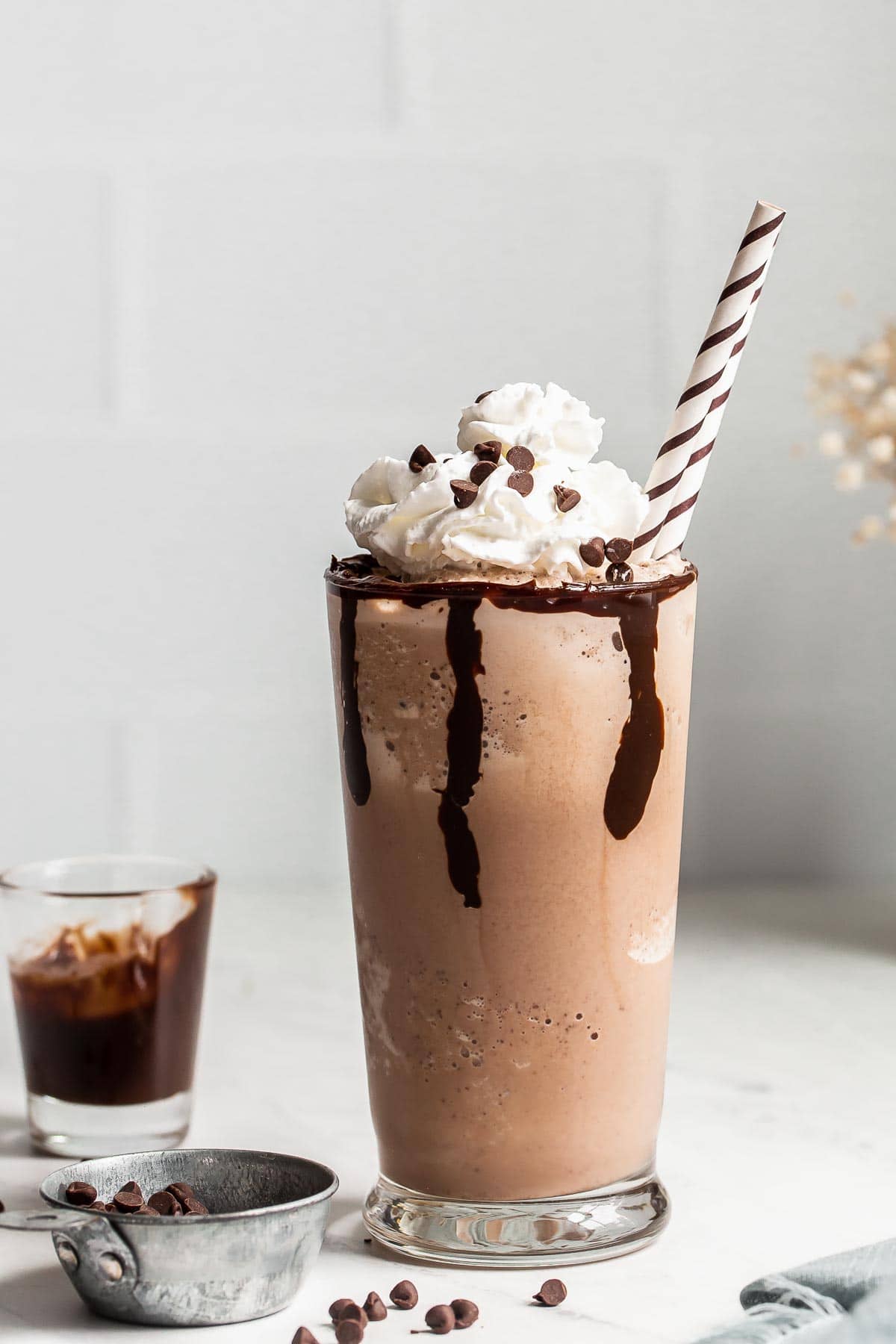 Chocolate chip frappe in a glass garnished with whipped cream and chocolate chips.