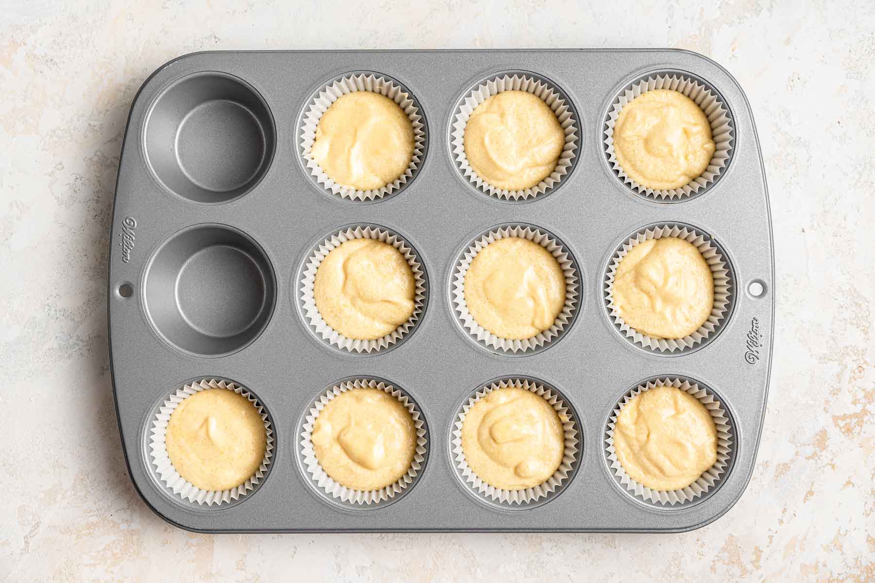 Ten cupcakes in a baking pan, raw.