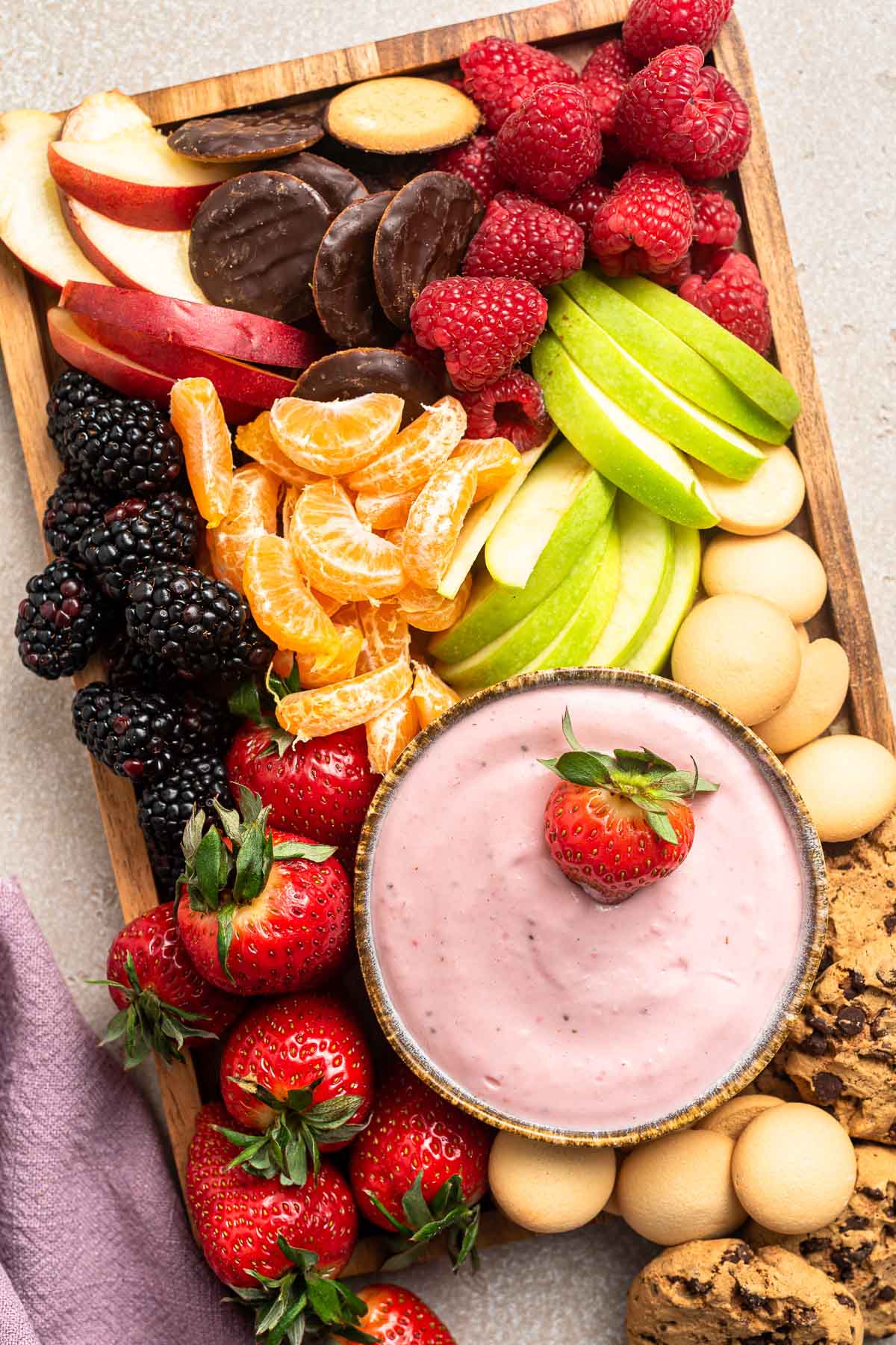 Fruit charcuterie board with pink fruit dip in middle.