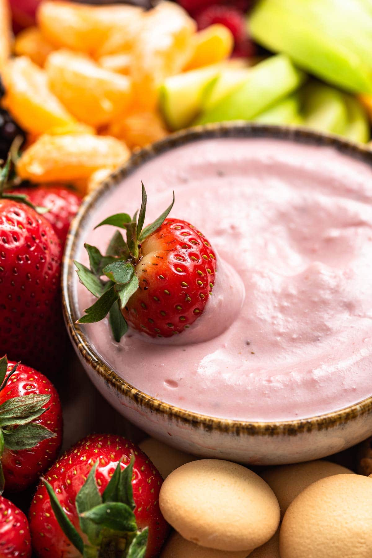 Pink fruit dip in a bowl with fresh strawberry on top.