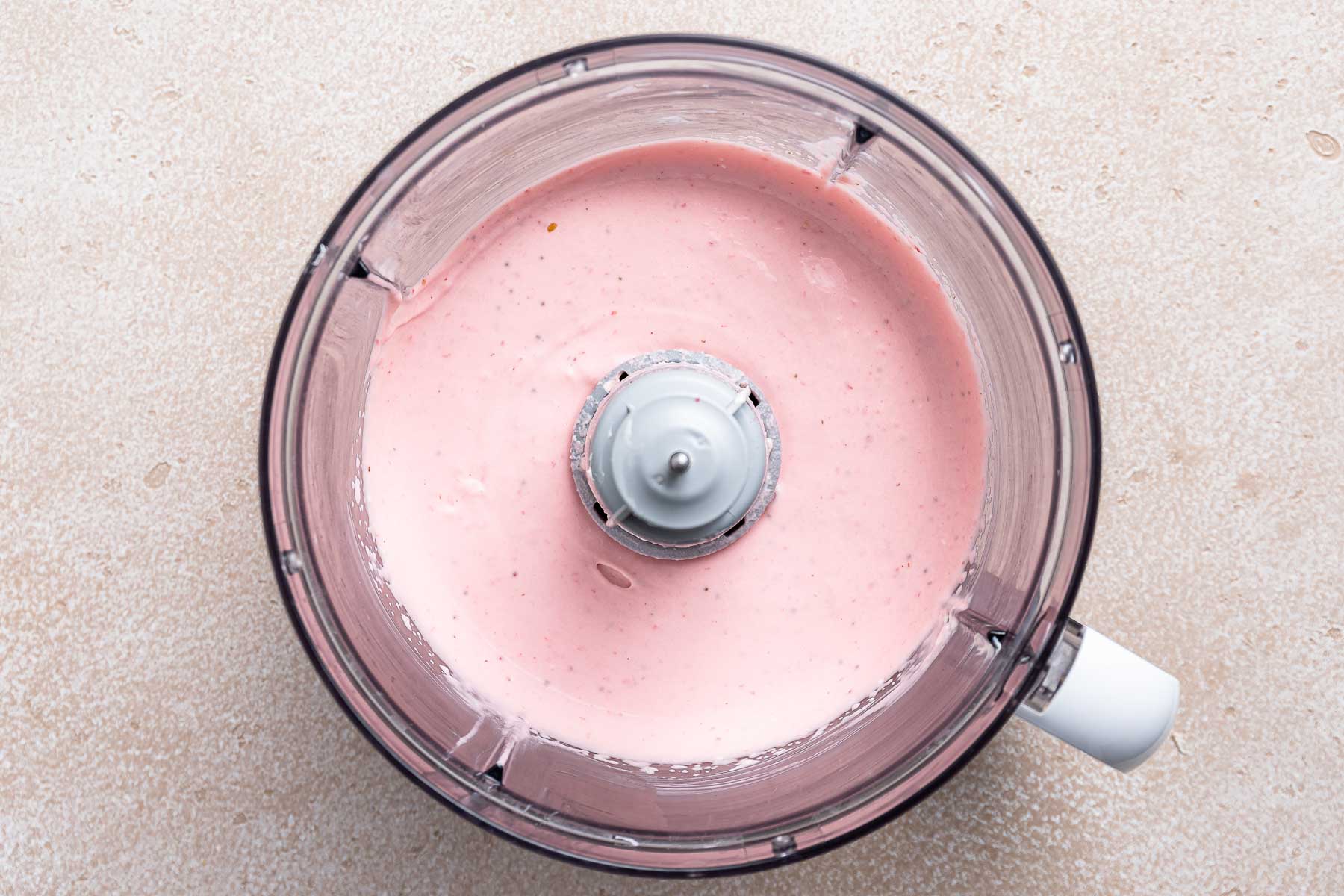 Pink fruit dip in food processor bowl.