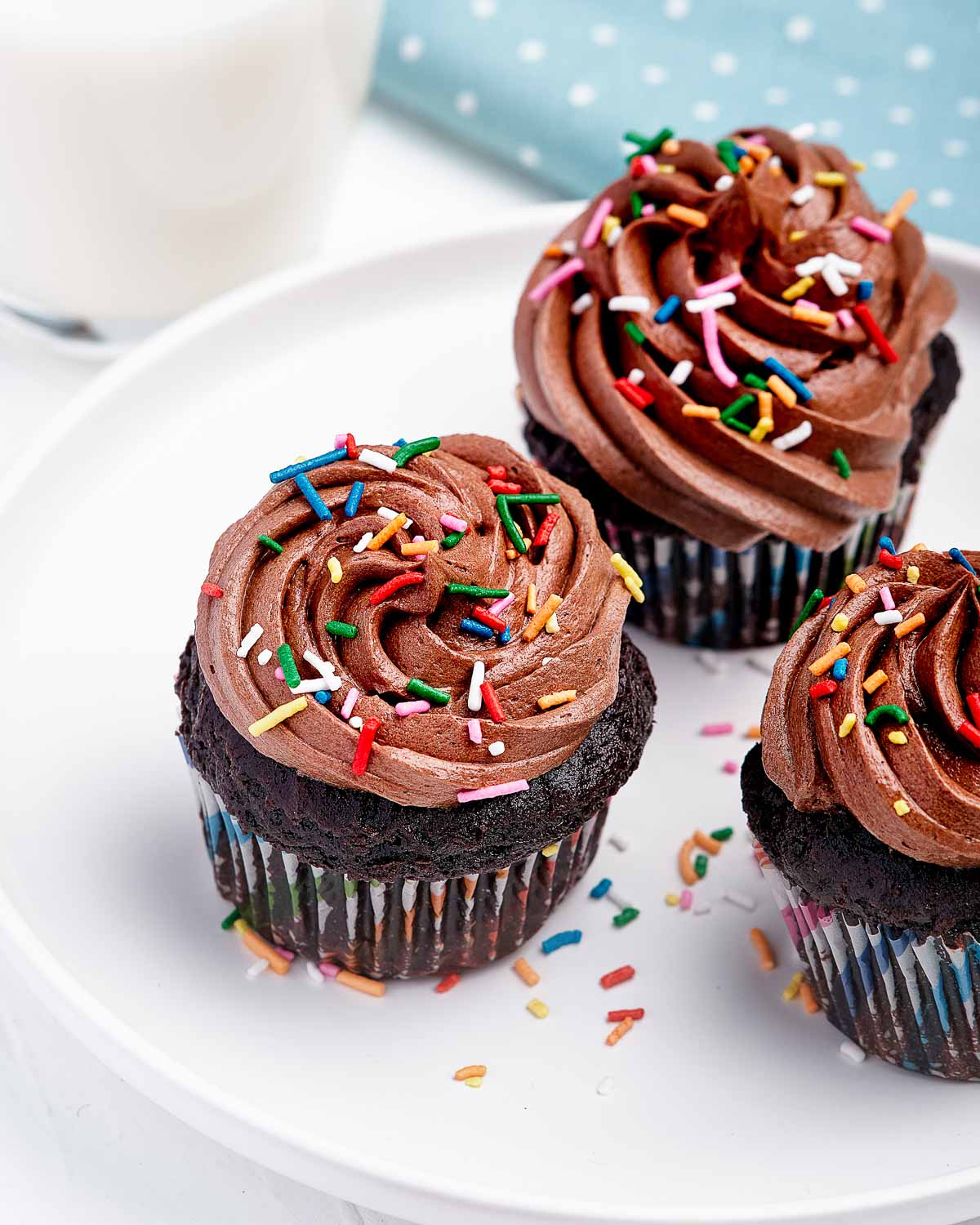 Plate of cupcakes with chocolate frosting and sprinkles.