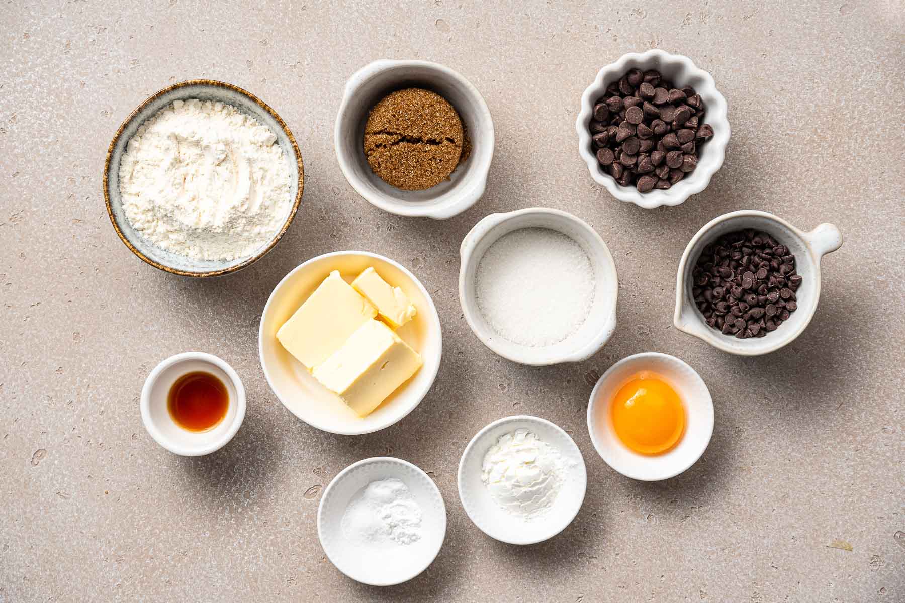 Baking ingredients in small bowls on white surface.