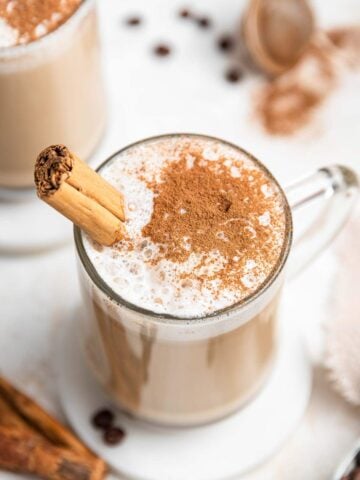 Latte with cinnamon dusted on top and cinnamon stick.