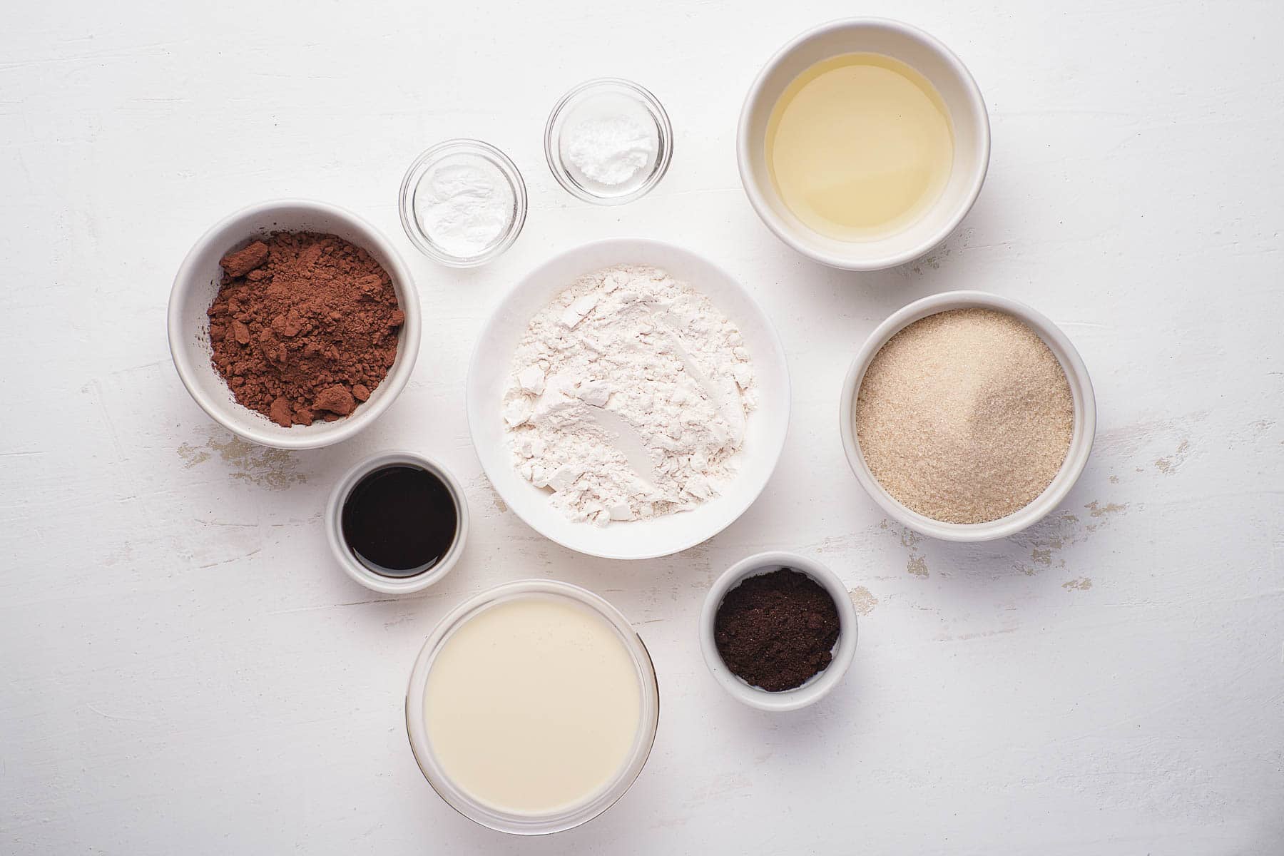 Ingredients for chocolate cupcakes on a white table in bowls.