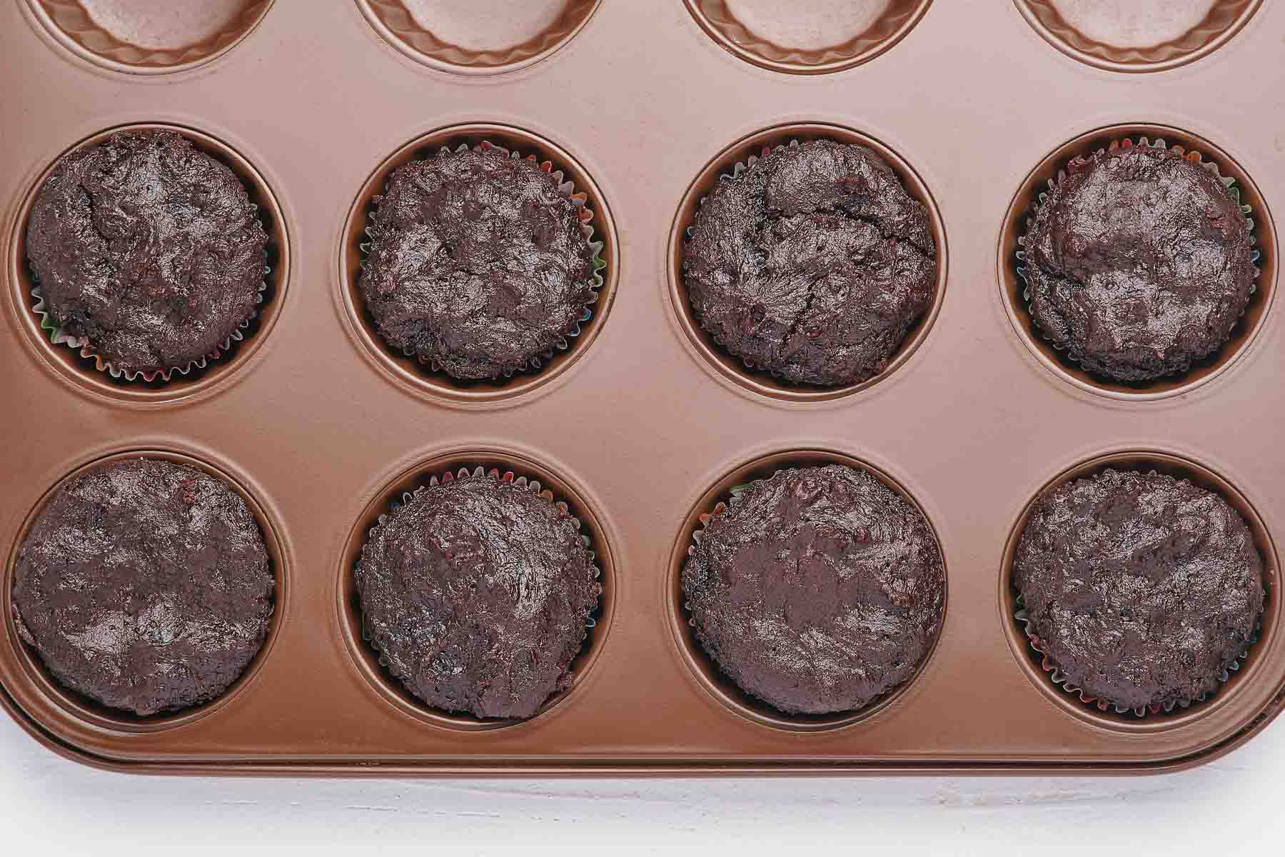 Eight baked chocolate cupcakes in a muffin pan.
