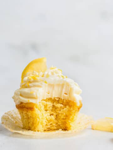 Single yellow cupcake with cream cheese frosting and lemon slice.