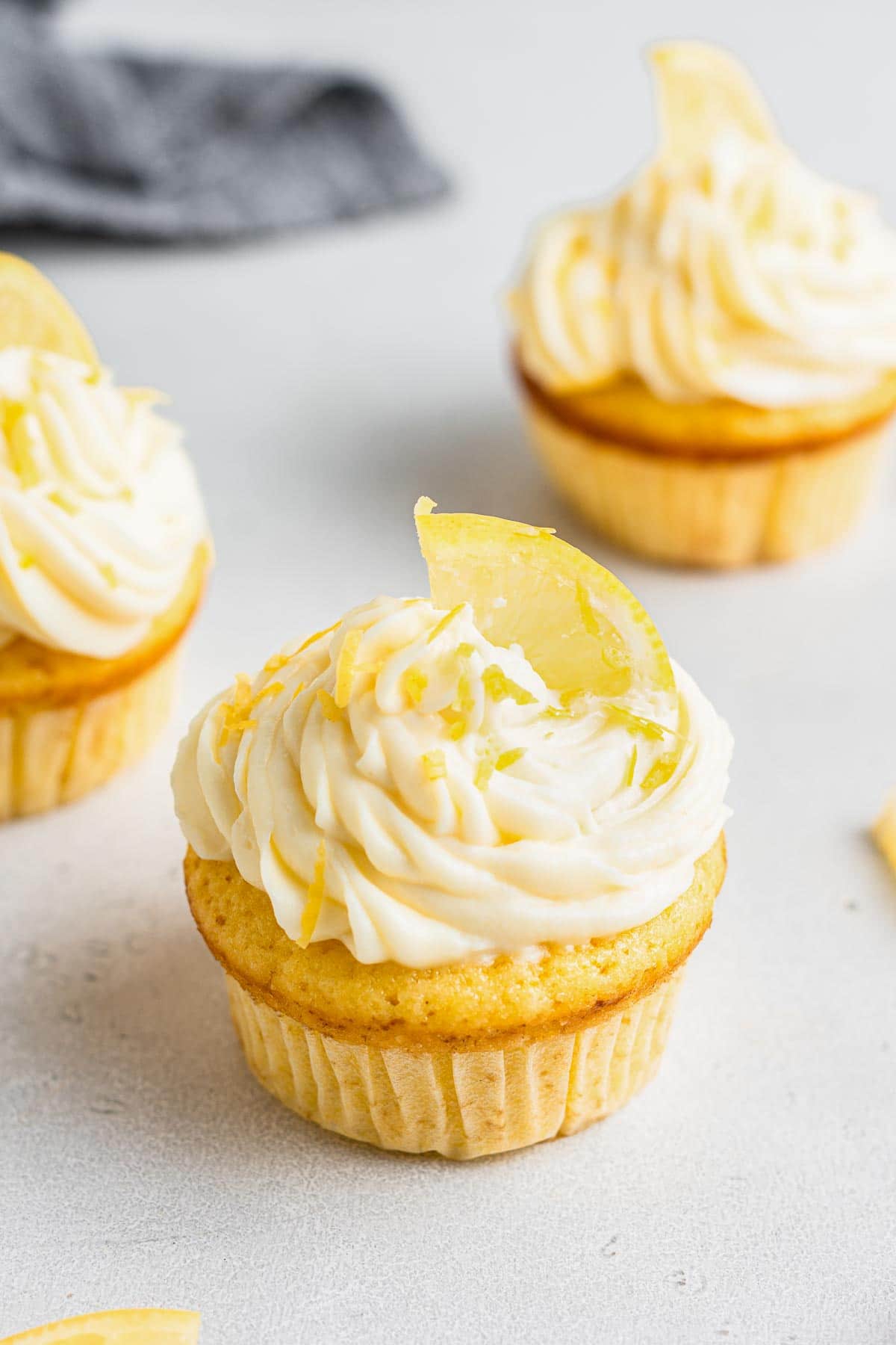 Lemon cream cheese frosting swirled on a cupcake with lemon slice.