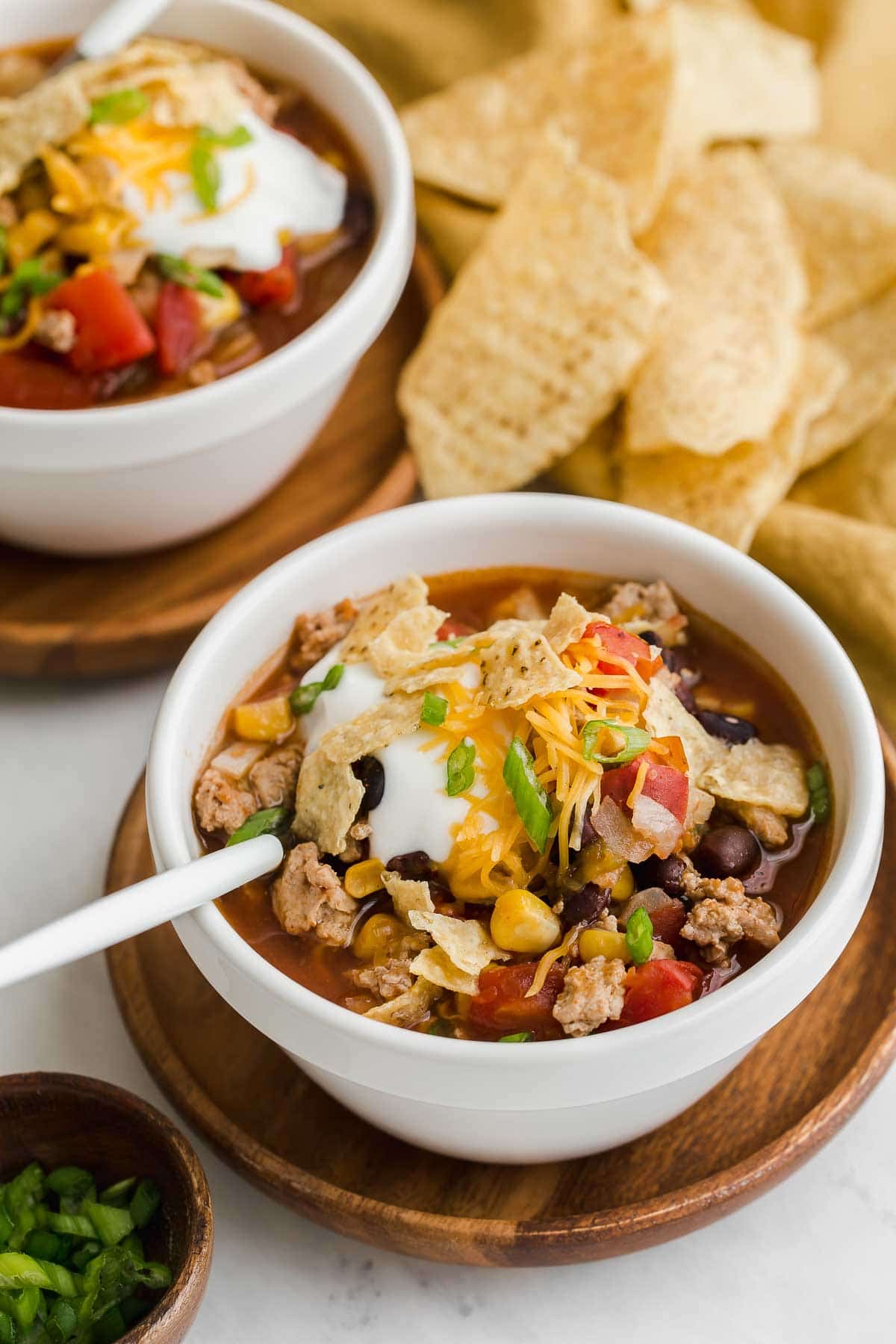 Two bowls of taco soup with tortilla chips on the side.