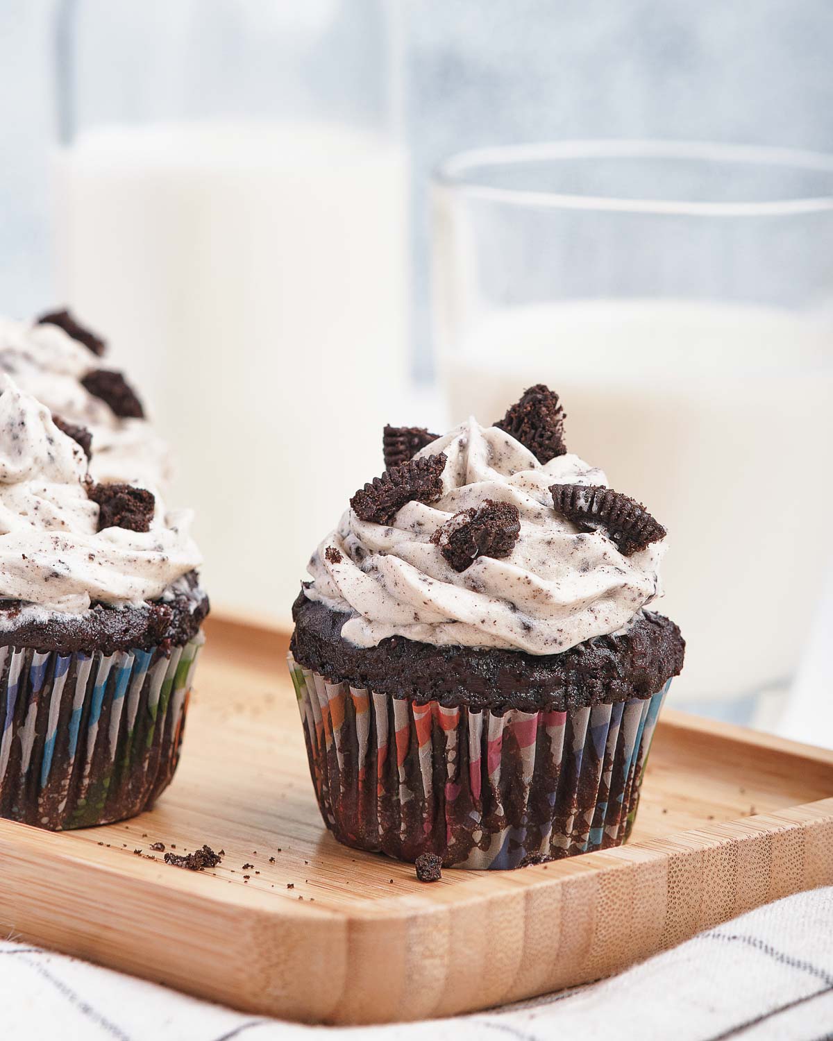 Chocolate cupcakes on wooden board with Oreo frosting and broken cookies on top.