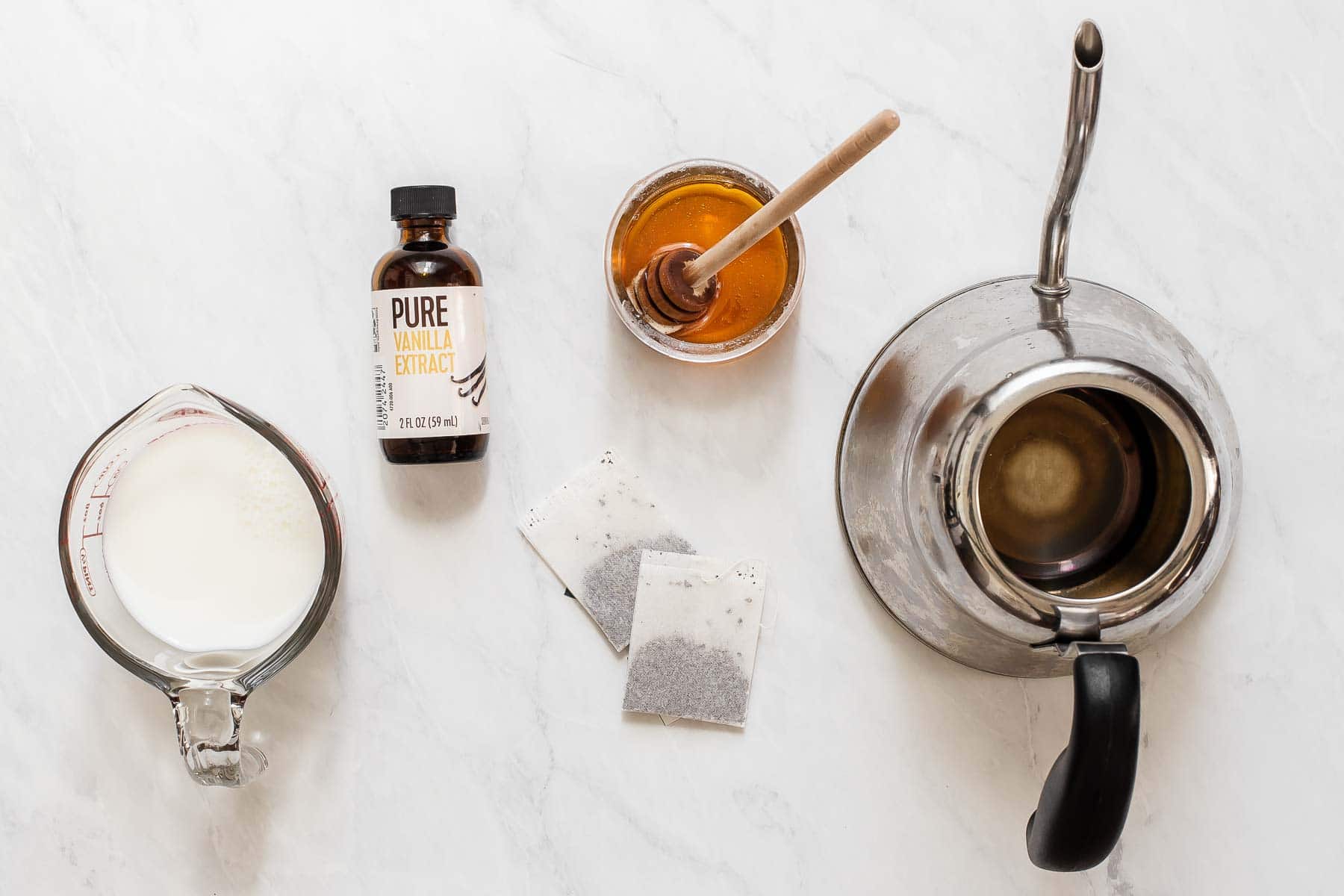 Ingredients to make iced London fog tea latte on white table.