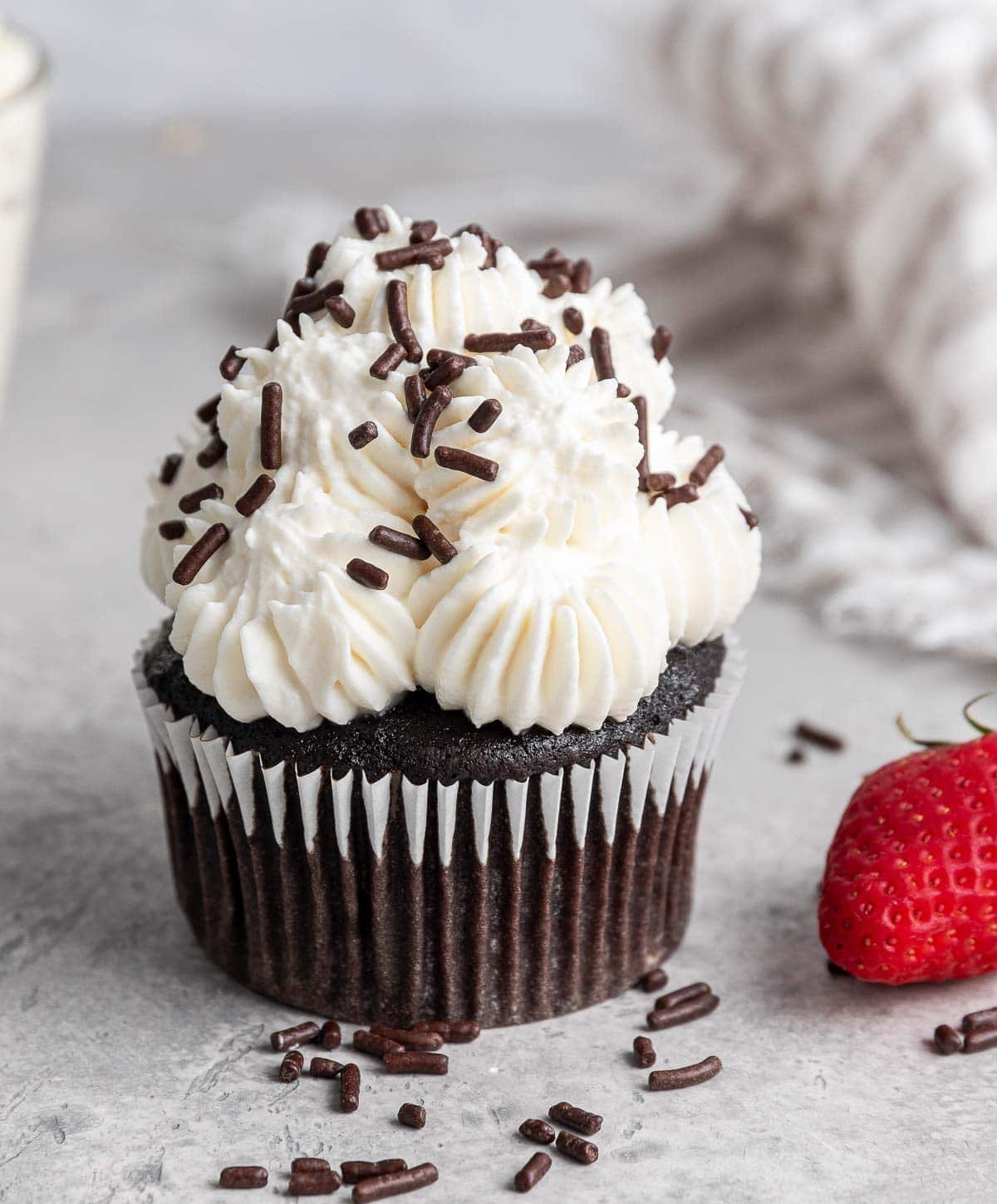 Chocolate cupcakes with white icing and chocolate sprinkles.