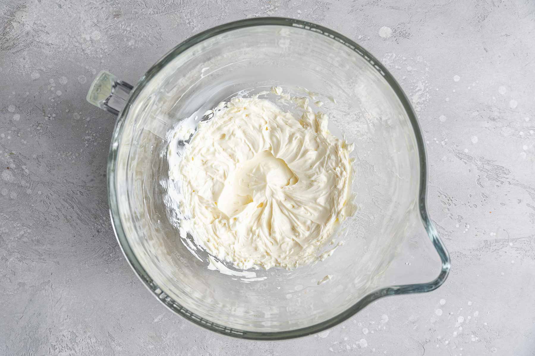 Cream cheese beating in a stand mixer bowl.