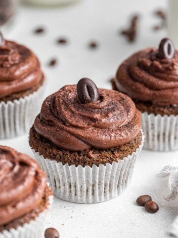 Up close photo of coffee cupcakes with chocolate frosting and espresso bean.