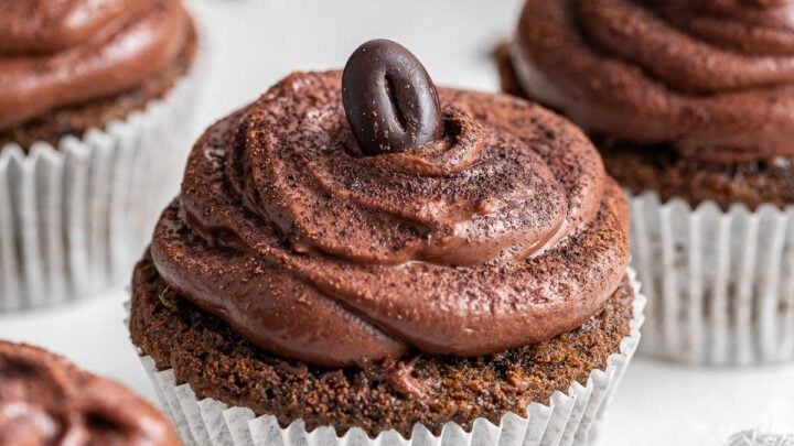 Up close photo of coffee cupcakes with chocolate frosting and espresso bean.