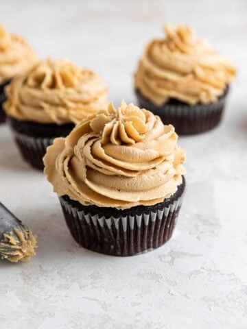 Peanut butter frosting piped on chocolate cupcakes.