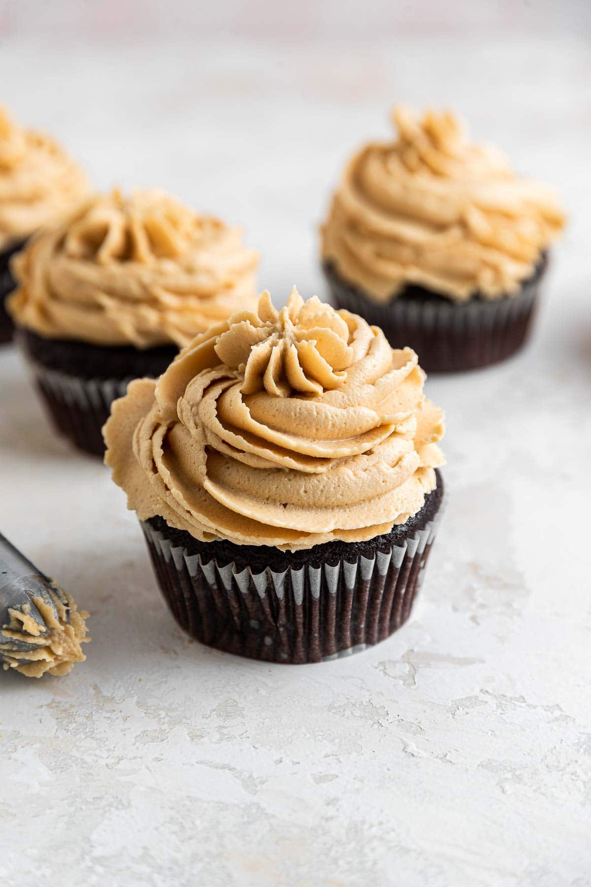 Peanut butter frosting piped on chocolate cupcakes.