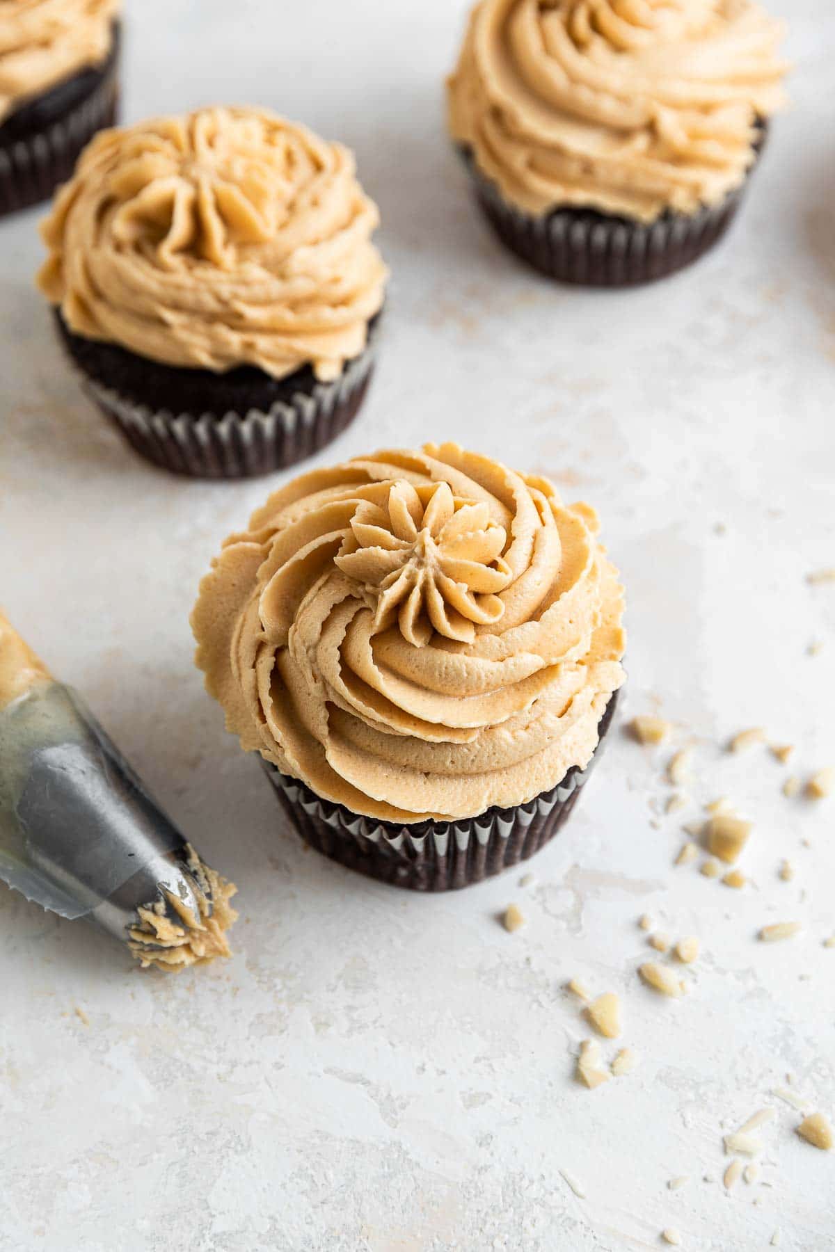 Four chocolate cupcakes with piped frosting on top.