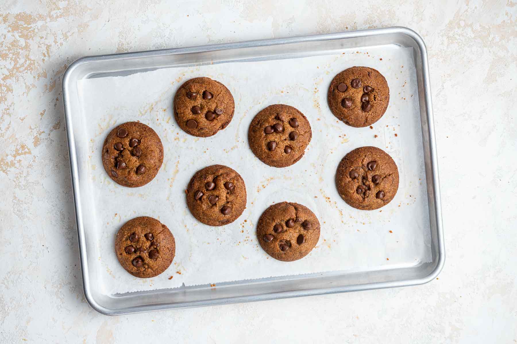 Eight healthy chocolate chip cookies with coconut oil on baking sheet.