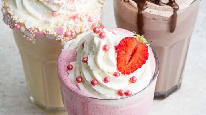 Image of 3 glasses of milkshakes: strawberry in front with chocolate and vanilla in the back.