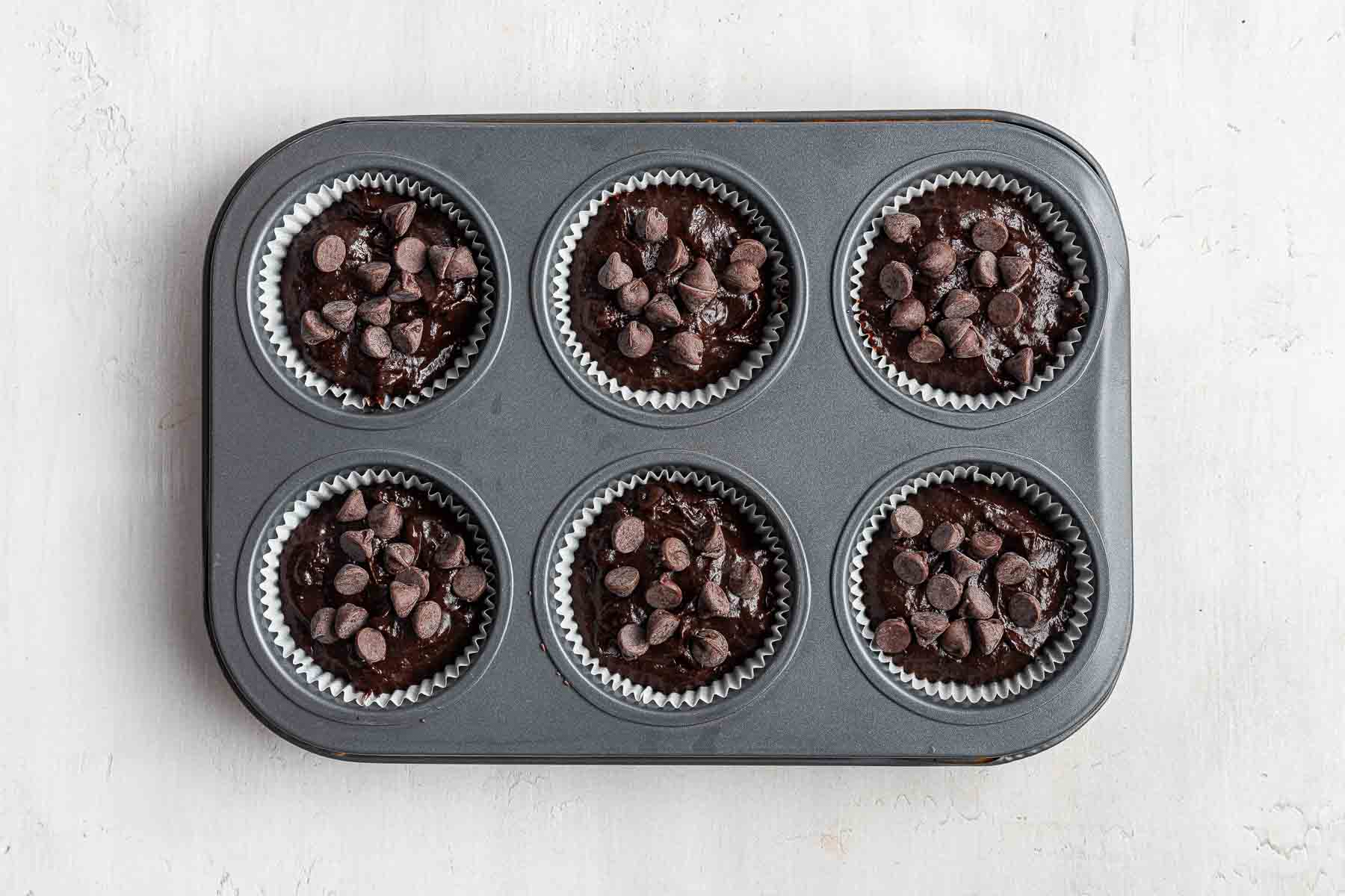 Six portion muffin tray with chocolate muffins about to be baked in oven.