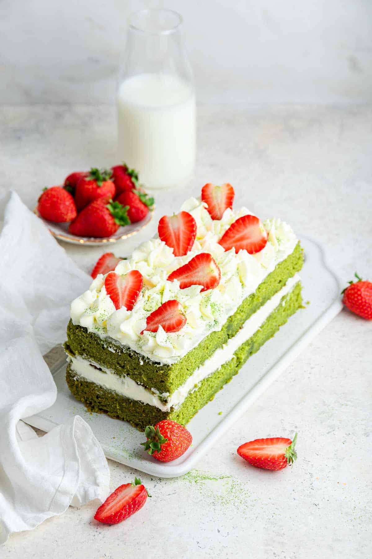 A layer cake made from a loaf pan, decorated with frosting and strawberries.