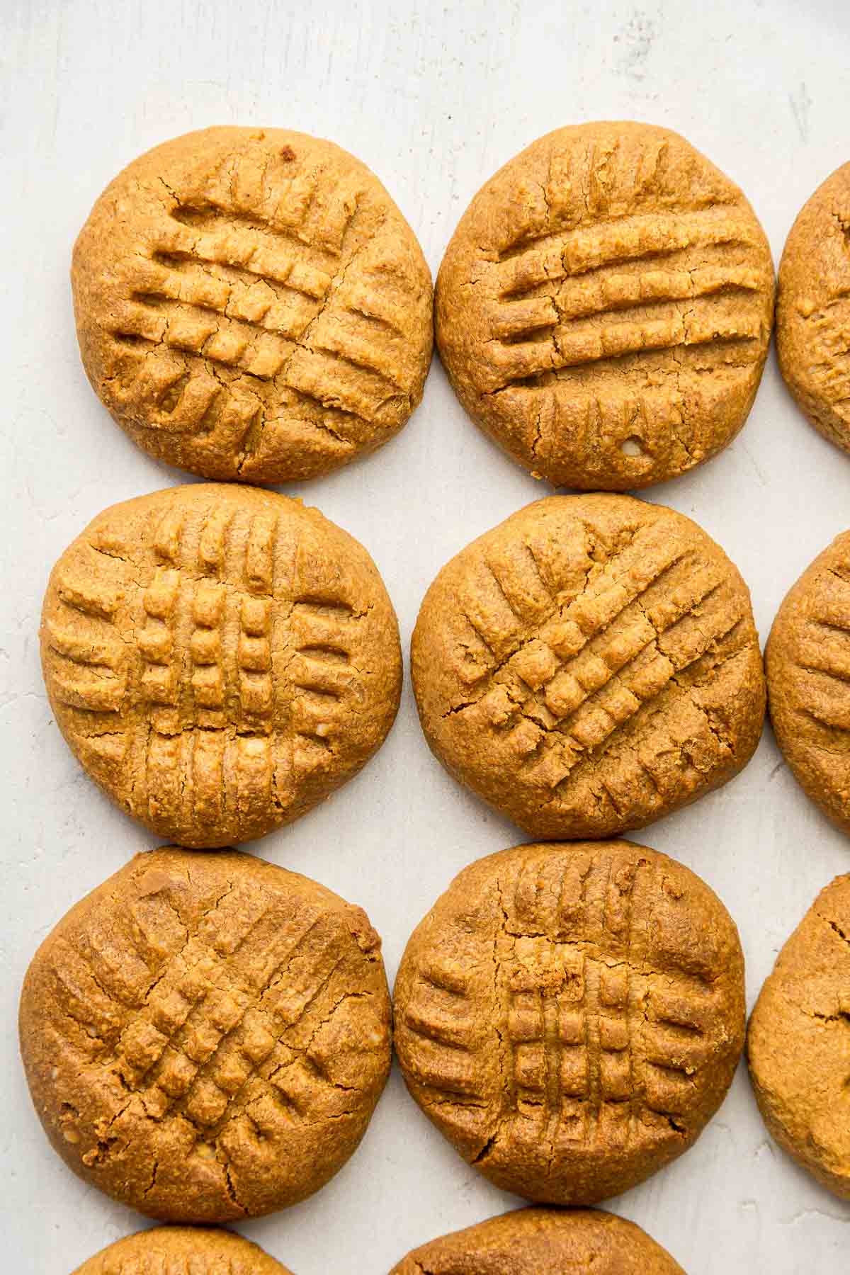 Overhead shot of six criss cross peanut butter cookies on white board.