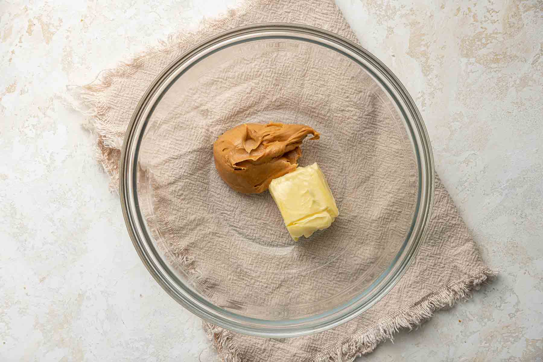 Bowl of peanut butter and butter on top of a kitchen towel.