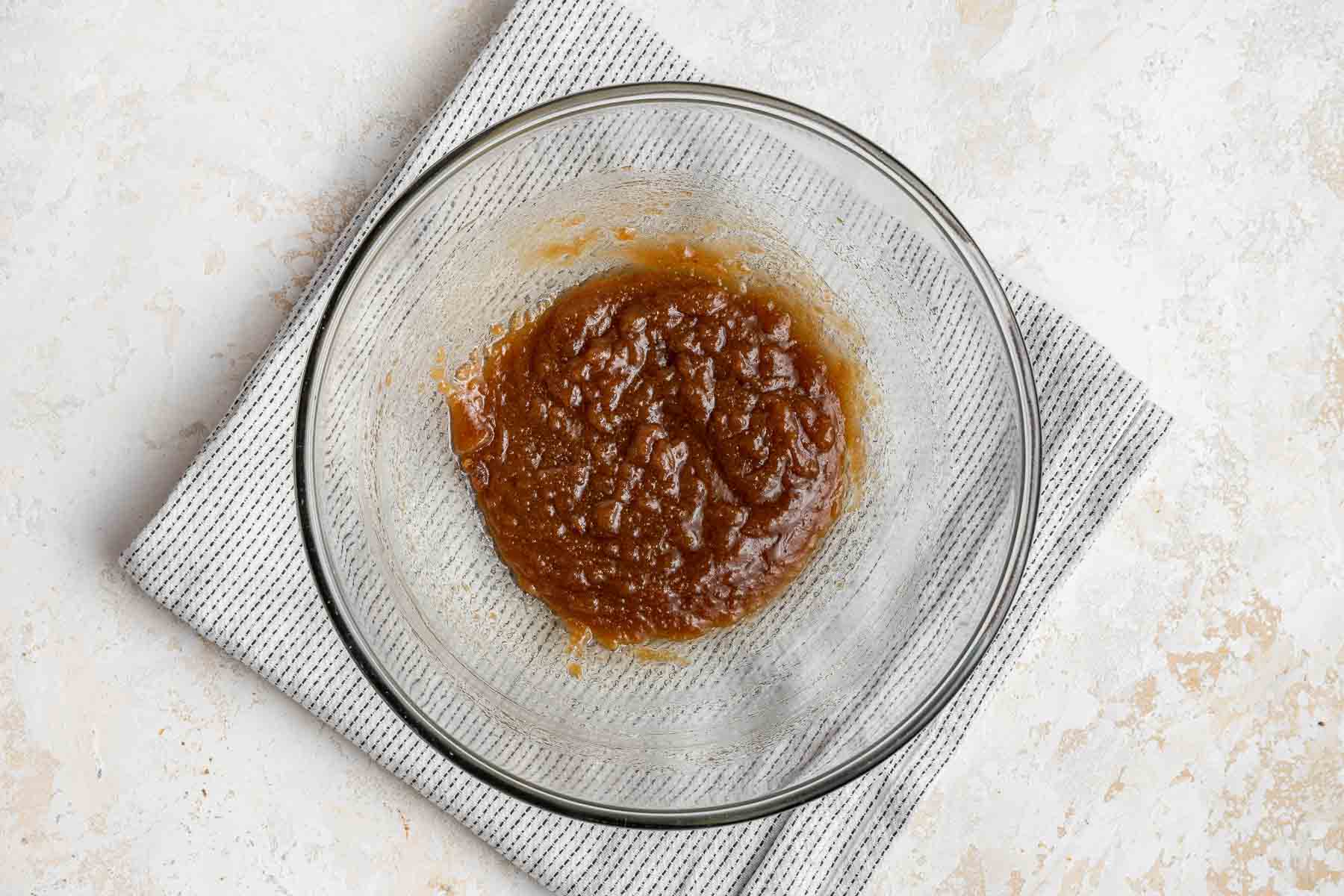 A clear glass bowl with melted butter, brown sugar and granulated sugar.