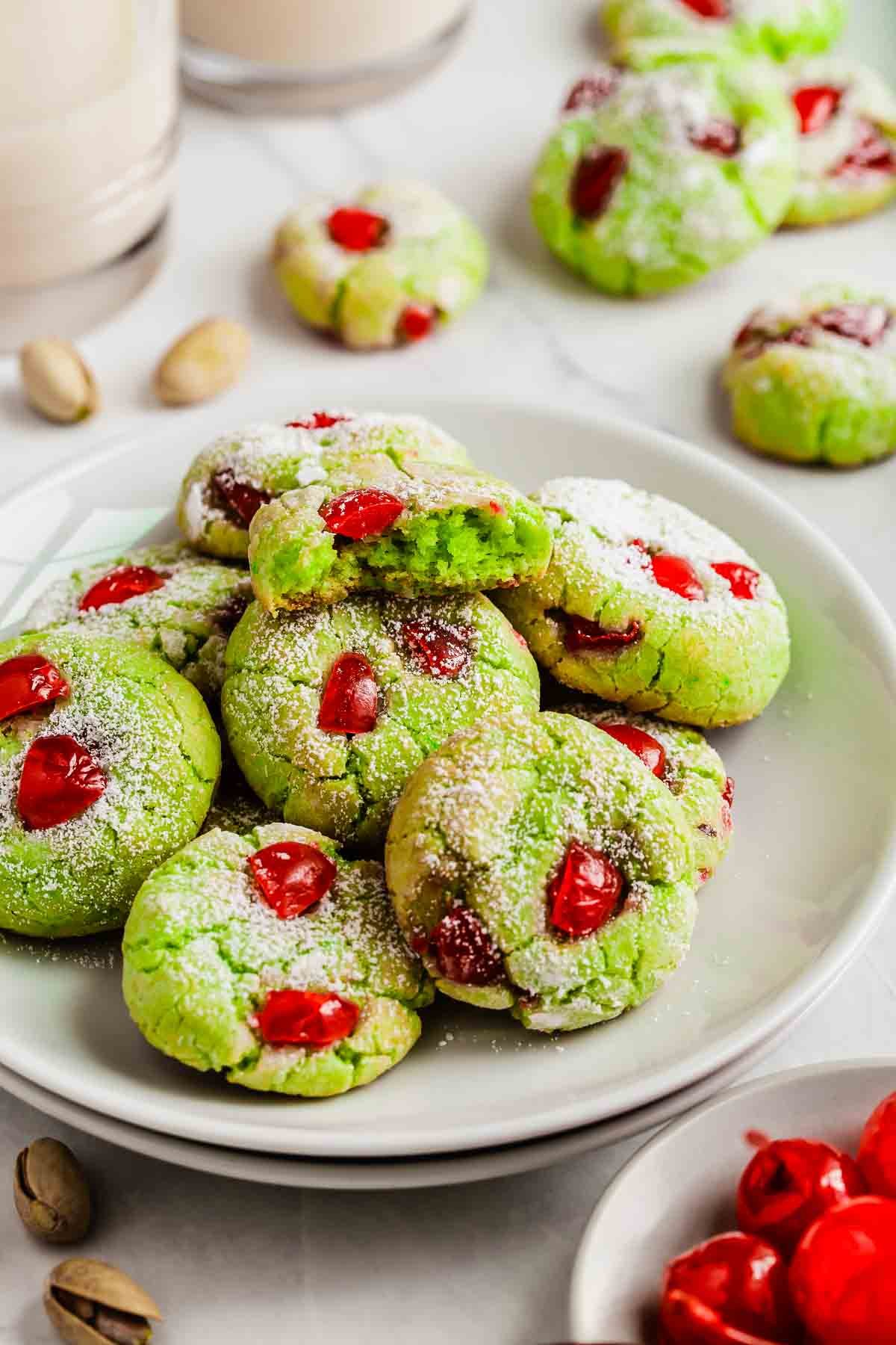 Plate of bright green pistachio pudding cookies with red cherries studded throughout.