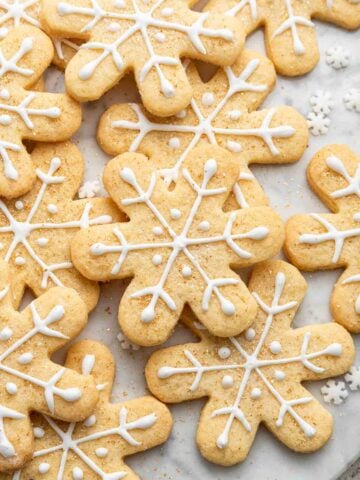 Overhead close up shot of decorated snowflake cookies on marble board.