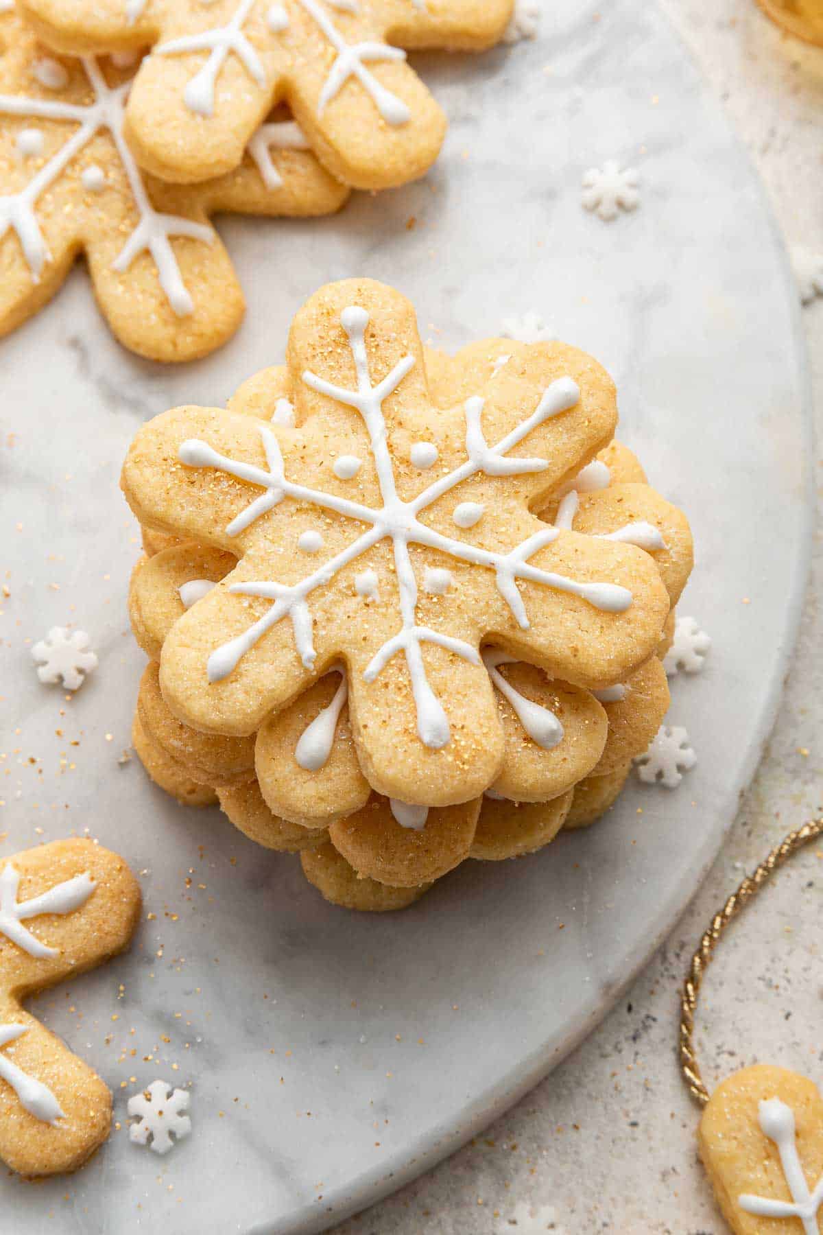 A stack of decorated snowflake cookies on marble board.
