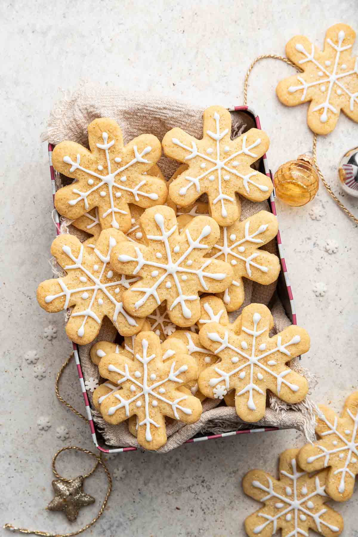 Cute box of decorated snowflake cookies on table.
