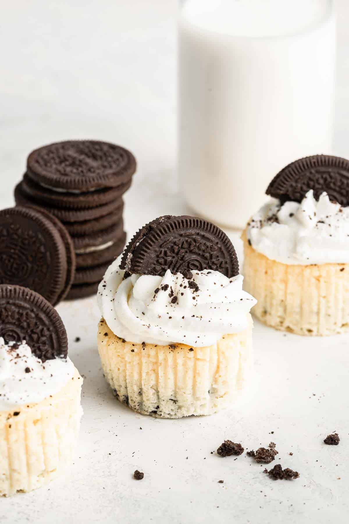 Oreo cheesecake cupcakes on a table garnished with whipped cream and half an oreo.