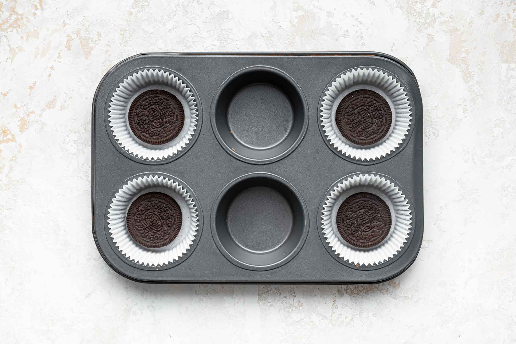 Four oreos in a muffin pan in liners.