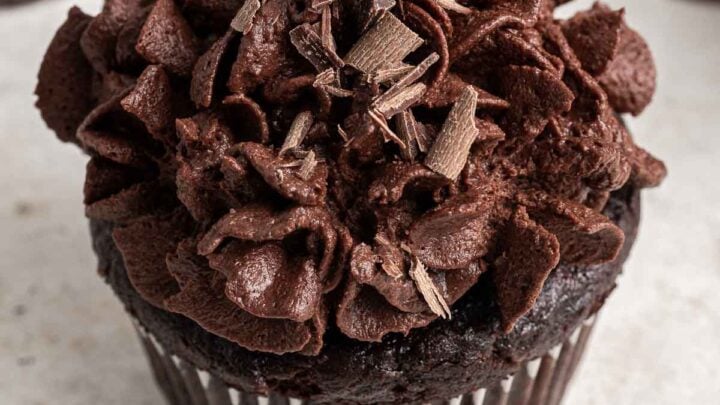 Close up of chocolate cupcake with piped chocolate whipped cream on top.