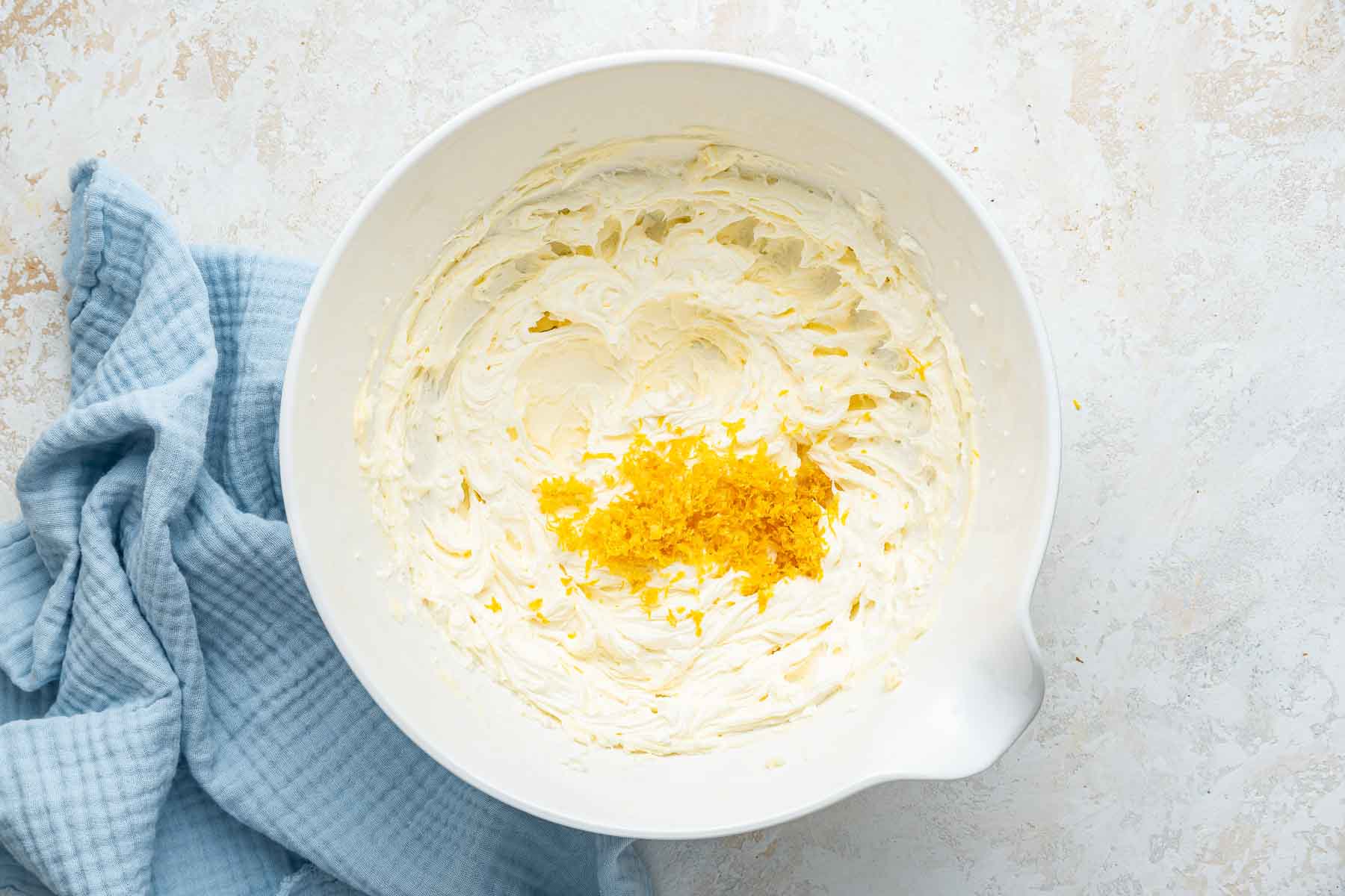 White bowl of freshly creamed butter with lots of lemon zest on top.
