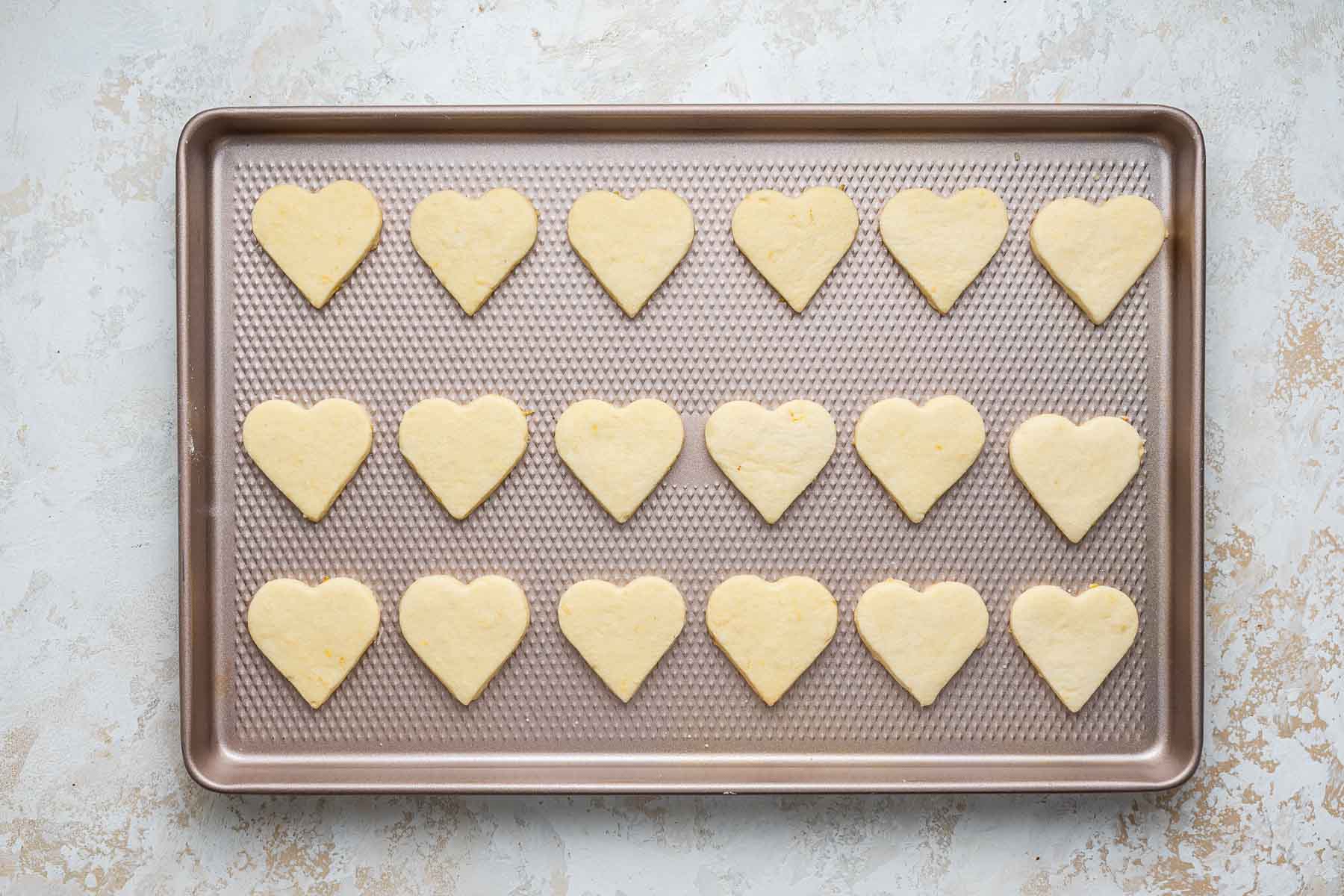 Freshly baked heart shaped treats on a baking sheet.