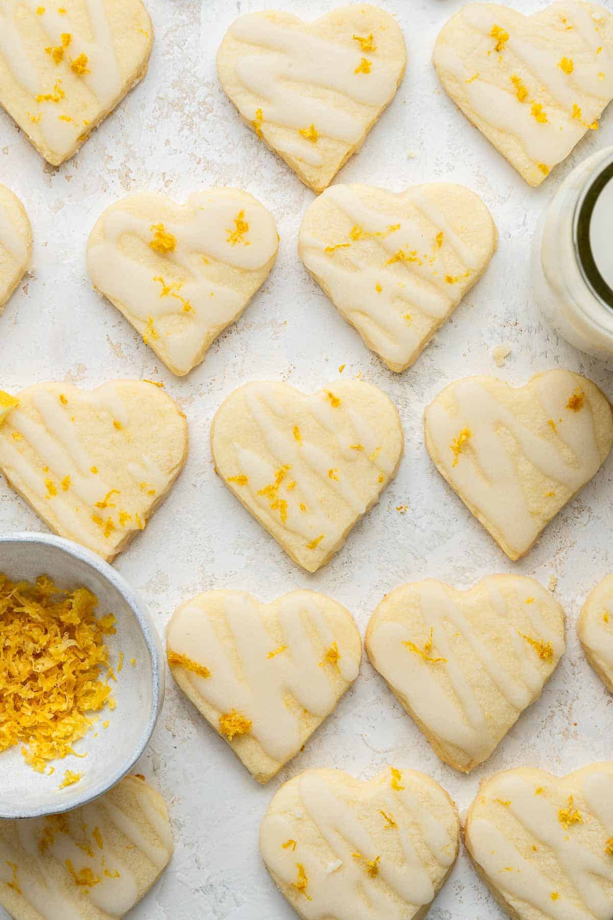 Neatly arranged heart cookies with lemon zest and glaze.