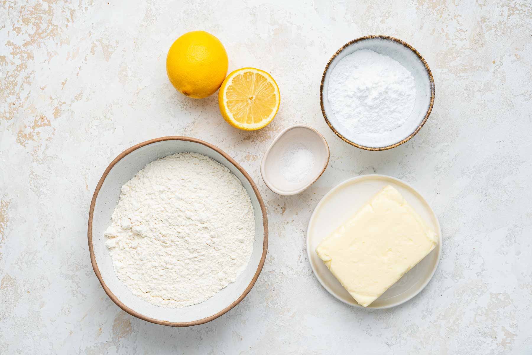 Overhead image of flour, cut lemon, butter, and salt.