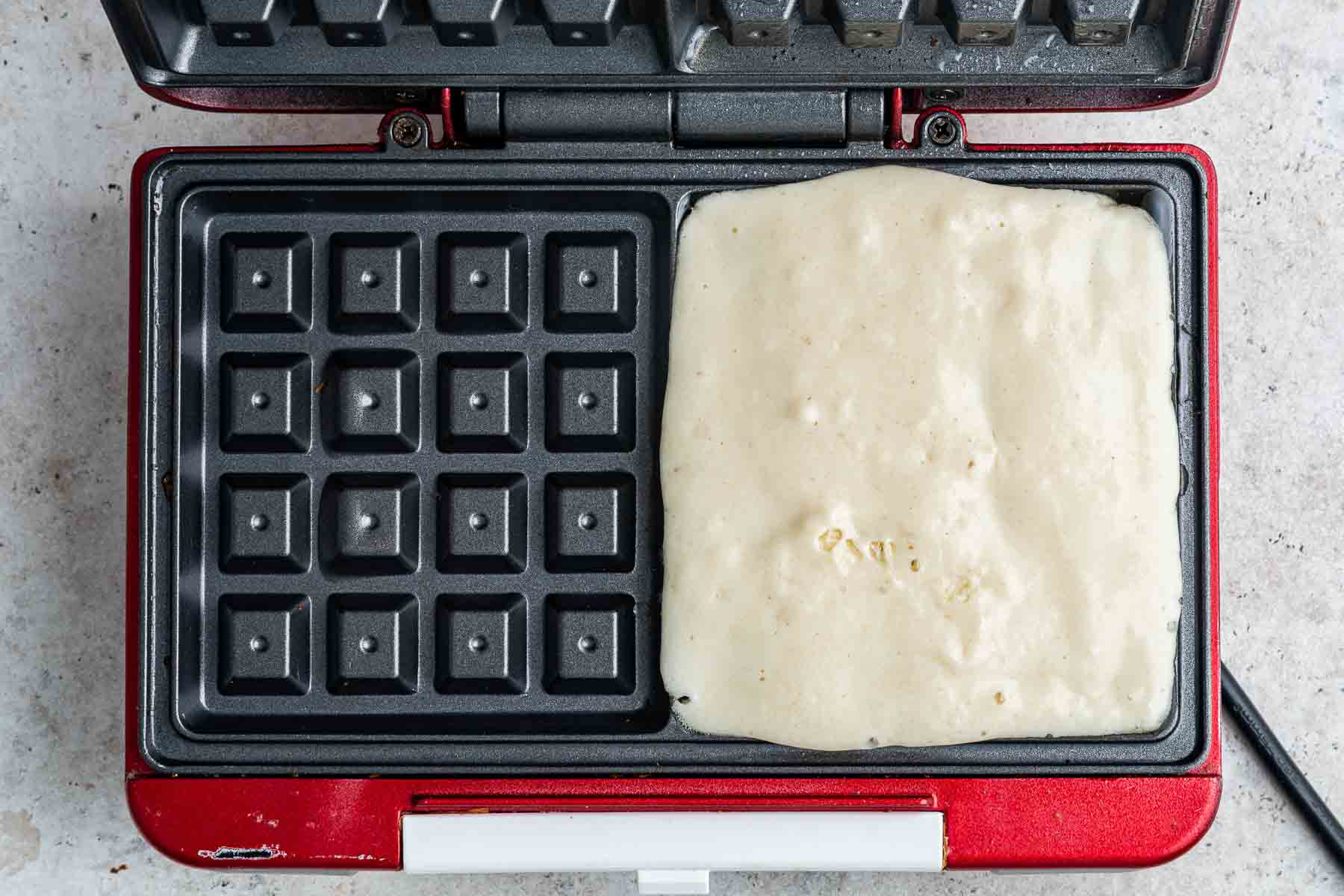 Raw batter on half of a square waffle iron.