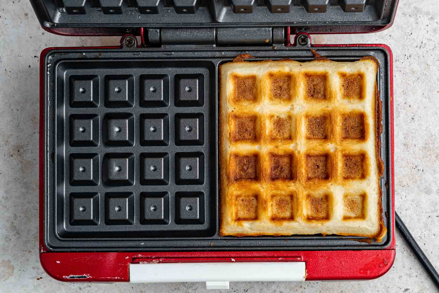 A single waffle freshly cooked on a waffle iron.