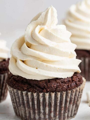 Close up photo of white swirled marshmallow frosting on a chocolate cupcake.