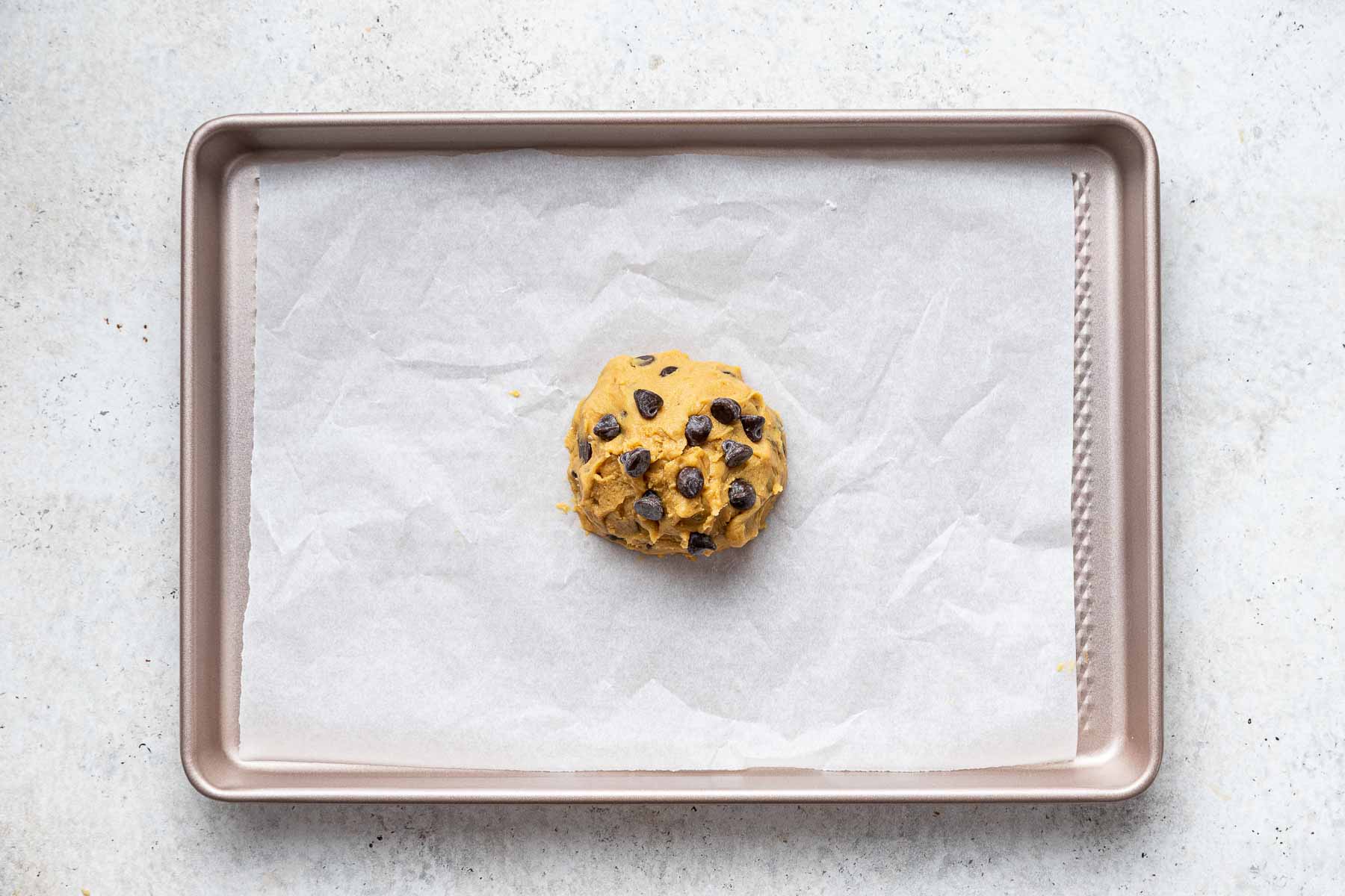 Pressing extra chocolate chips on a raw cookie before baking.