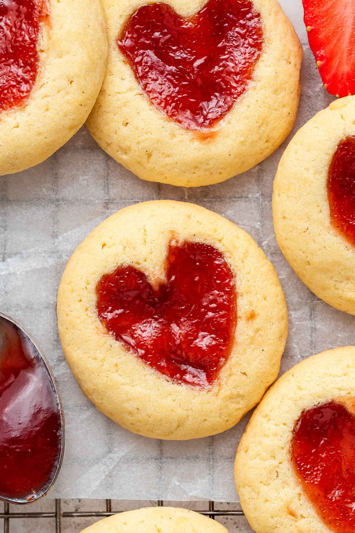 Close up image of yellow cookies with red heart centers of jam.